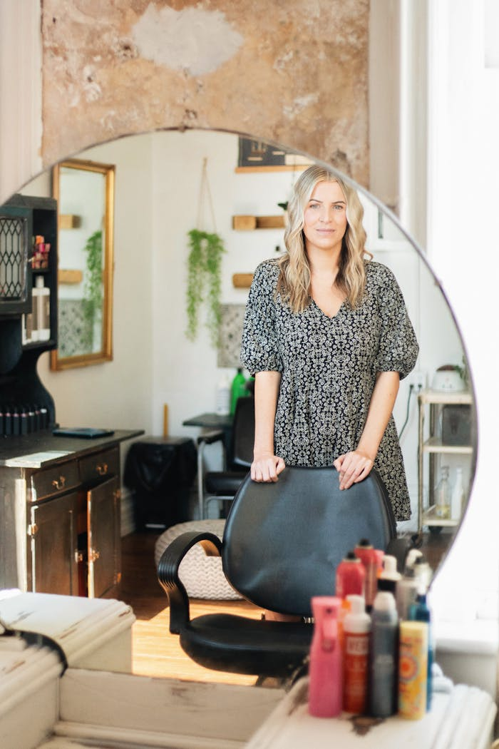 Portrait of a female hair stylist in a Brevard, NC salon, showcasing natural light and professional setting.