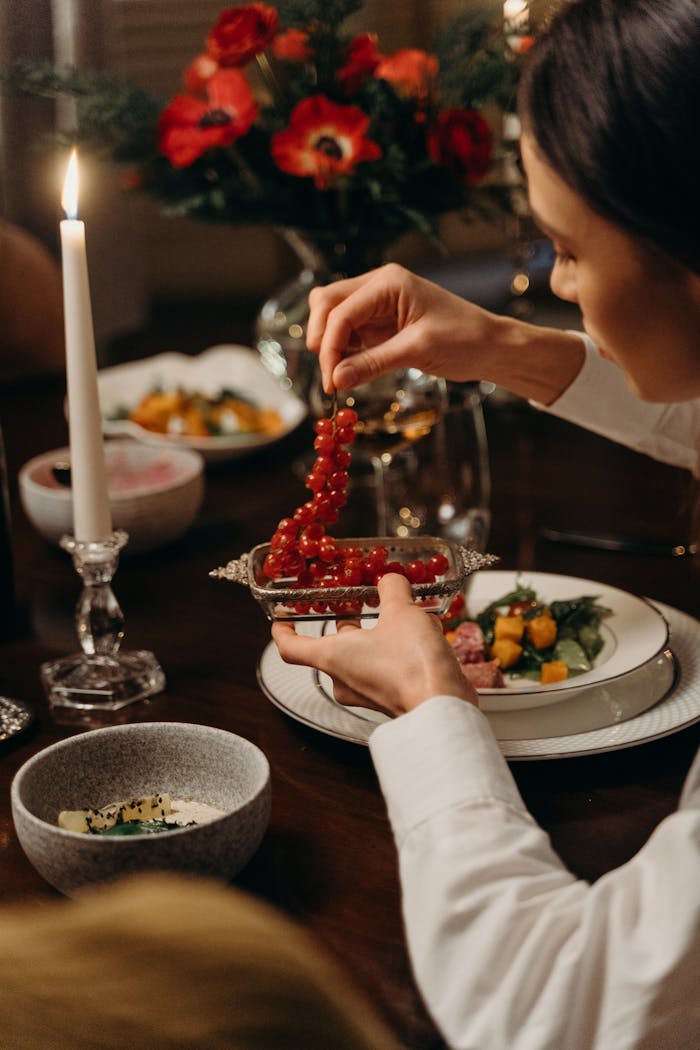why-choose-us A woman elegantly serves redcurrants during a candlelit dinner.